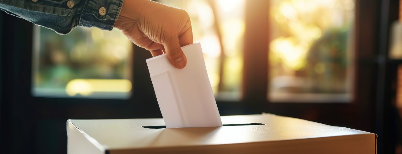 Hand drops ballot into ballot box on election day
